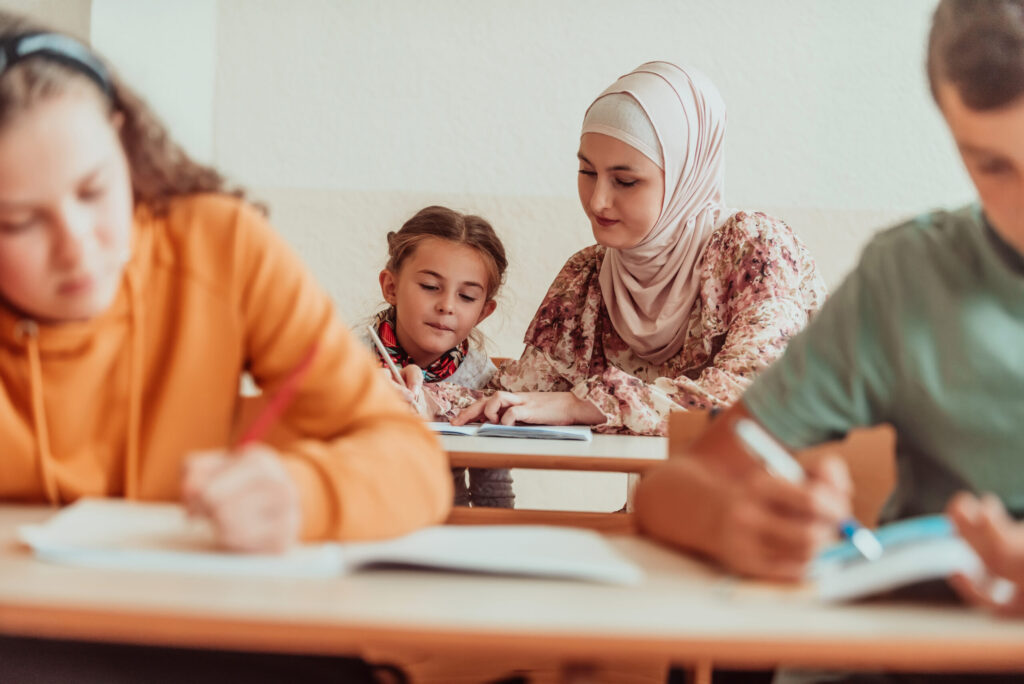 Female hijab muslim teacher helps school kids to finish they lesson. Selective focus .High quality photo