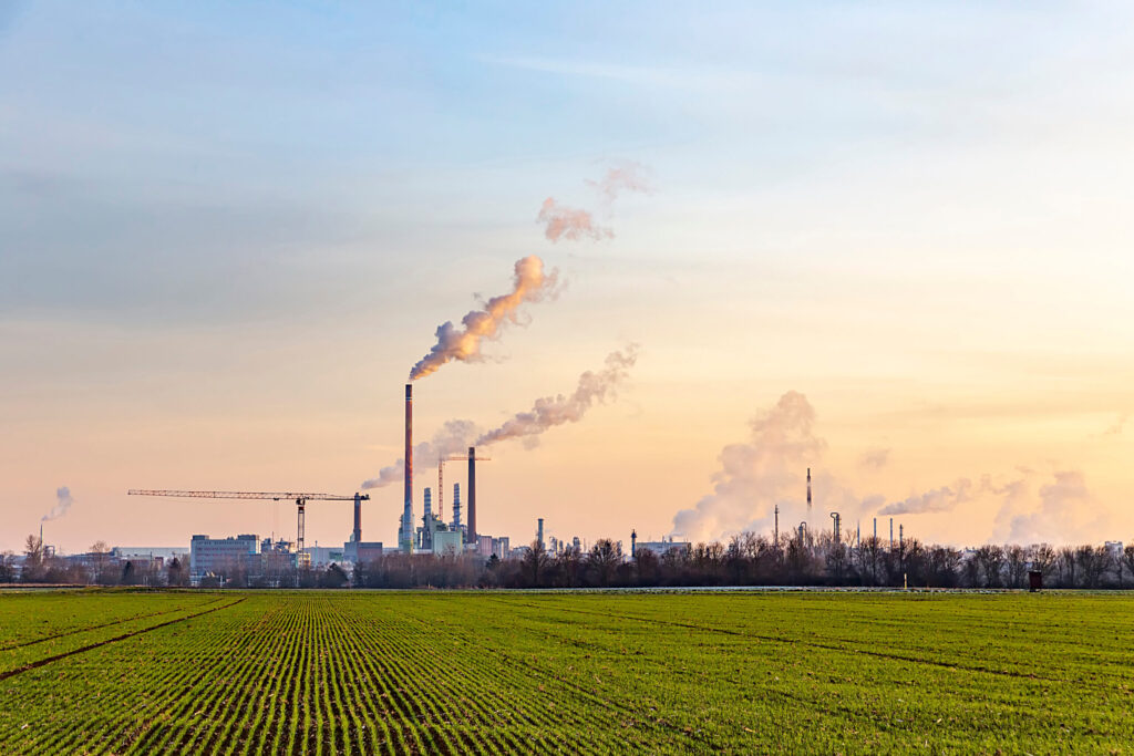 industry complex in Frankfurt in late evening with  fields and smoking chimney in winter